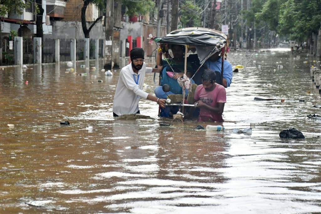 Residents wade through a flooded street following heavy monsoon rains in Guwahati on August 4, 2026